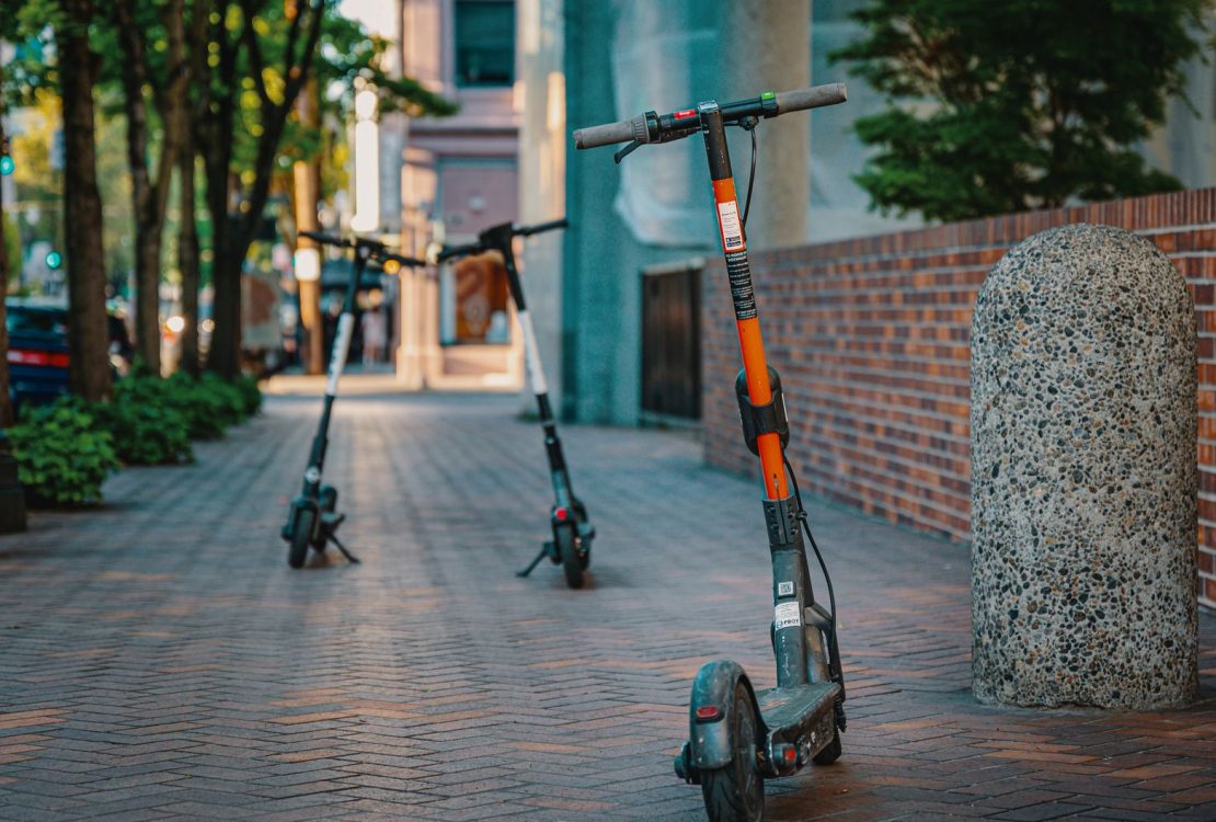 Patinetes elétricos estacionados em uma calçada urbana, representando uma opção de mobilidade nas cidades.