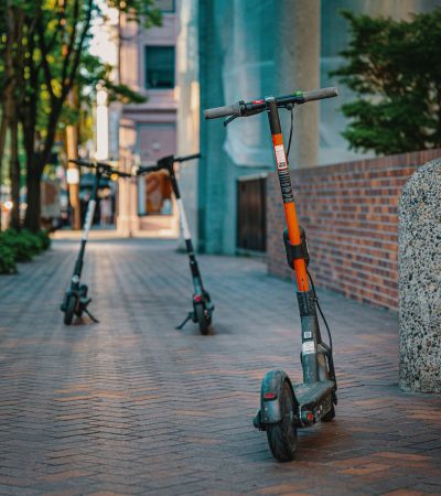 Patinetes elétricos estacionados em uma calçada urbana, representando uma opção de mobilidade nas cidades.