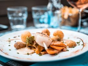 Prato elaborado com vieiras, legumes e batatas servido em um restaurante francês.