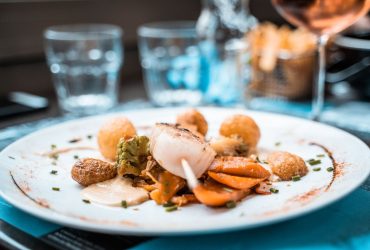 Prato elaborado com vieiras, legumes e batatas servido em um restaurante francês.