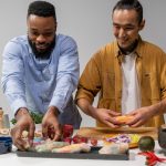 Duas pessoas preparam rolinhos primavera veganos em uma cozinha.